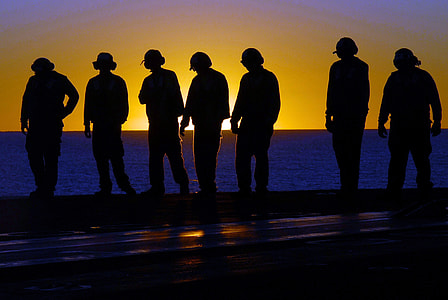 silhouette of men standing on seashore thumbnail