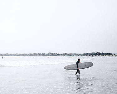 man carrying long surfboard while walking on water thumbnail