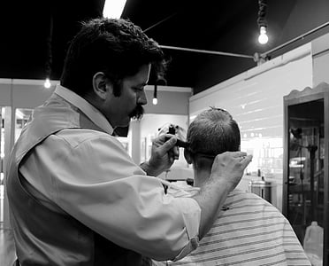 grayscale photography of man doing haircut on boy thumbnail