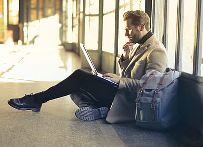man sitting near glass window laptop on his lap thumbnail