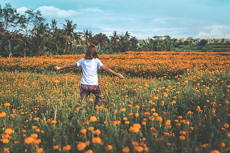 woman spreading her arms wide open walking in marigold field thumbnail