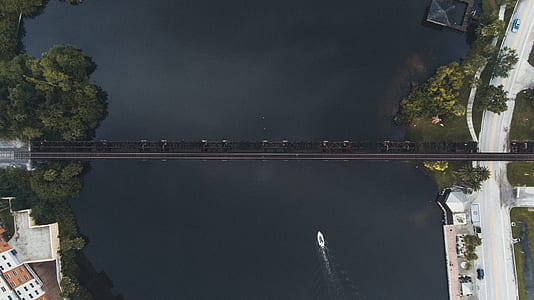 aerial photo of white boat approaching black bridge thumbnail
