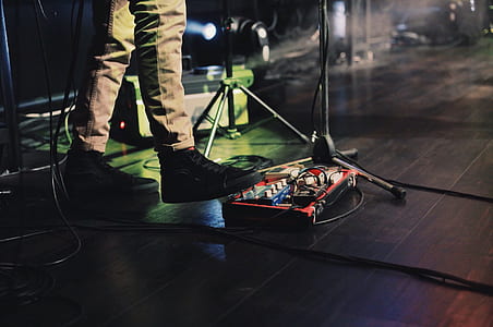 person wearing black high-top sneakers standing beside black cable and microphone stand thumbnail