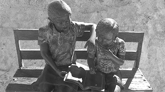 girl and toddler reading book statues thumbnail