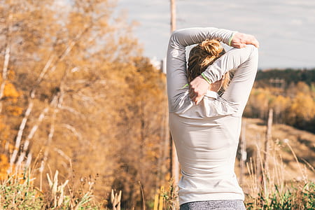 woman standing on green grass stretching her arms taken during daytime thumbnail