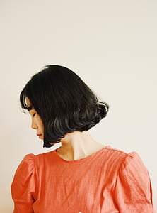 woman looking right standing beside white painted wall thumbnail