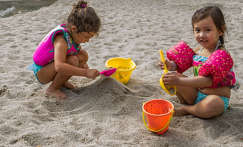 two toddler girls sitting on sand while playing during daytime thumbnail