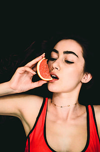woman wearing red and black sleeveless top holding red and yellow fruit thumbnail