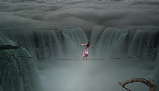 photograph of woman about to cross on rope above waterfalls thumbnail