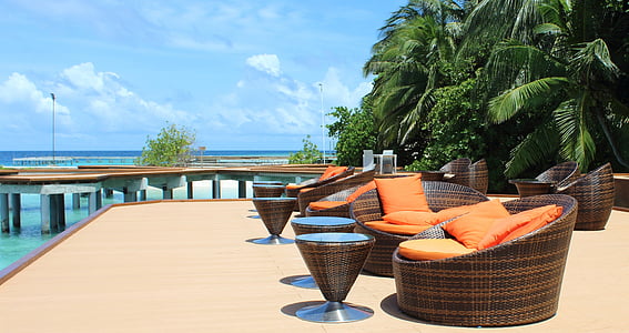 two brown wicker chairs near ocean under blue sky thumbnail