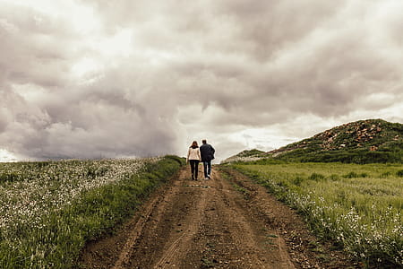 Man in Black Jacket Near Woman in White Jacket Surrounded by Flowers thumbnail