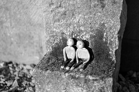 two figurines sitting on gray stone thumbnail