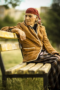 woman wearing brown jacket sitting on brown wooden bench thumbnail