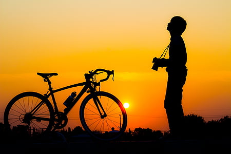 silhouette of man standing near road bike thumbnail
