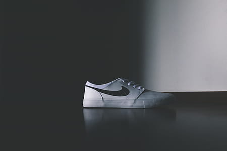 unpaired white and black Nike shoe on top black surface photo thumbnail