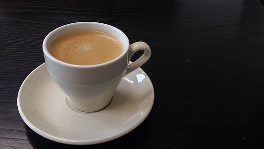 white teacup with coffee in saucer on black wood surface thumbnail