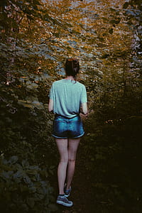 woman walking on pathway surrounded by plants thumbnail