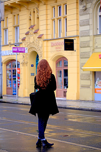 woman standing beside asphalt road and buildings thumbnail