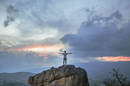 man on top of gray rock formation thumbnail