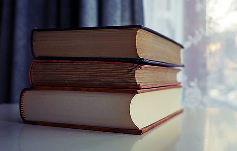 Three Piled Books on White Wooden Table thumbnail