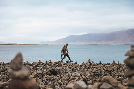 A young caucasian hiker on a stoney shore of a mountain lake thumbnail