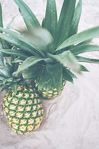 two pineapple fruits on gray sand thumbnail