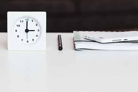 black pen between white desk clock and smartphone thumbnail
