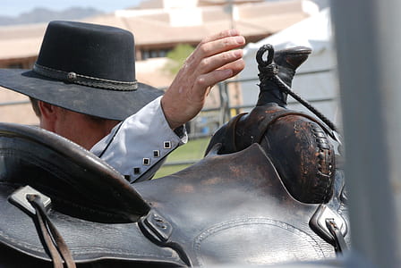 person to hold black leather horse saddle thumbnail