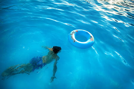 Person Swimming Under Body of Water Near Blue Inflatable Ring thumbnail