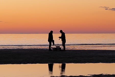 silhouette of man and woman standing on shore thumbnail