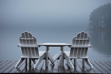 white wooden table with lounger chairs on wooden dock above water thumbnail