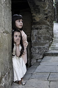 girl in white dress covering her mouth beside girl in beige dress thumbnail
