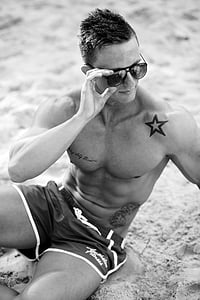 grayscale photo of man sitting on seashore thumbnail