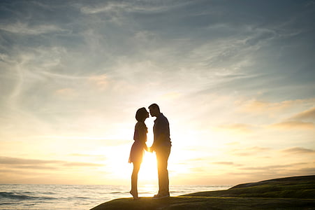 silhouette of man and woman facing each other near body of water thumbnail