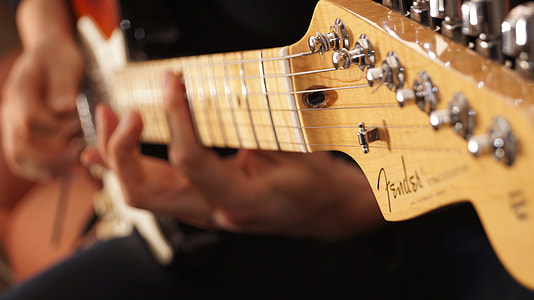 person playing brown Fender electric guitar thumbnail