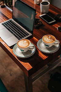 two cappuccino beside MacBook placed on table thumbnail