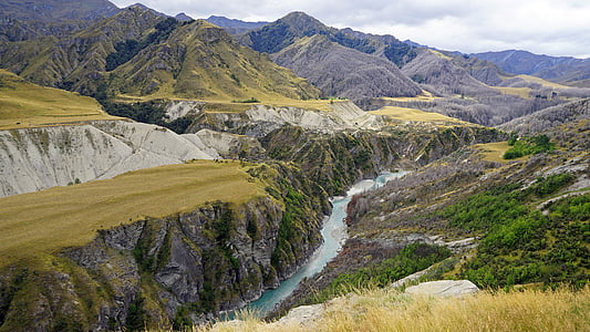 river between mountain under gray sky thumbnail