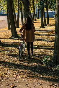 Woman Holding Bicycle Near Trees thumbnail