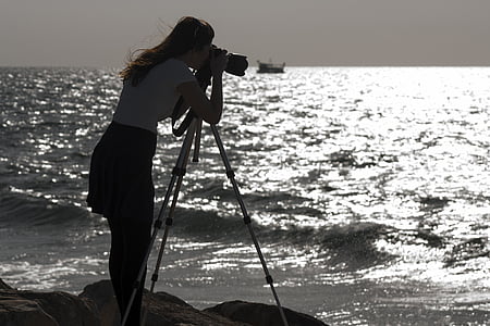 woman taking a photo on rock formation through the ocean thumbnail