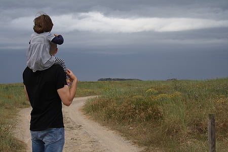 man in black shirt and blue jeans carrying children on green grass field during daytime thumbnail