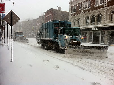 gray garbage truck clears the road with snowplow thumbnail