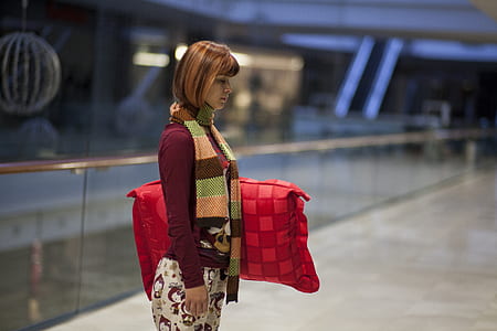 woman holding red pillow standing near glass fence thumbnail