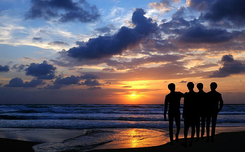 silhouette of four person facing the ocean thumbnail