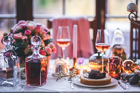 two glass decanter filled with wine on table with plate of pies and wine glasses thumbnail