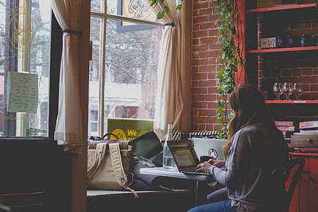 woman typing on laptop near window thumbnail
