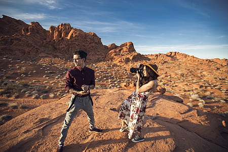 woman holding black DSLR camera while taking shot man in maroon dress shirt during daytime thumbnail