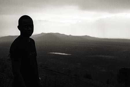 silhouette photo of boy looking mountain during daytime thumbnail
