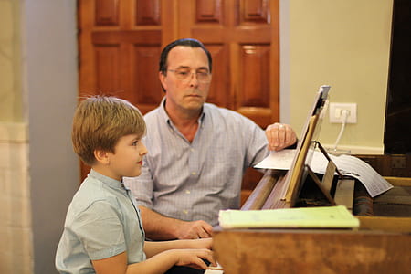 man watching kid playing piano in room thumbnail