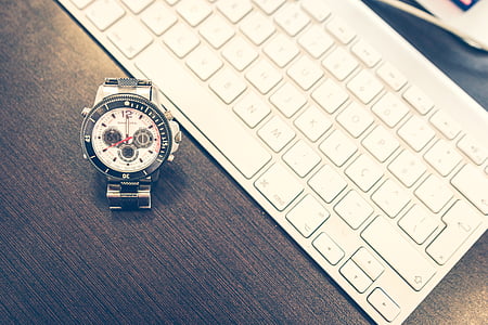 chronograph watch beside Apple Wireless keyboard on wooden surface thumbnail