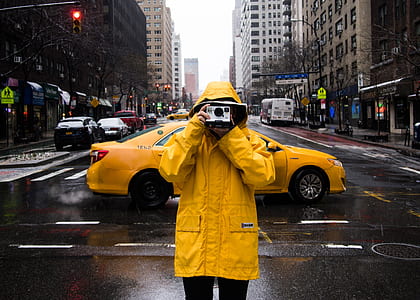 person with raincoat taking photo in the middle of the street thumbnail